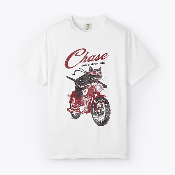 Black cat riding a red motorcycle with script text reading Chase your dreams on a white Comfort Colors t-shirt